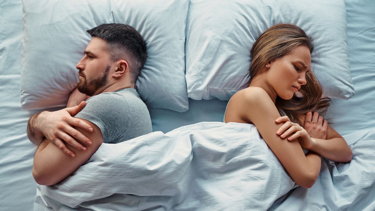 Férfi és nő hátat fordítva egy ágyban