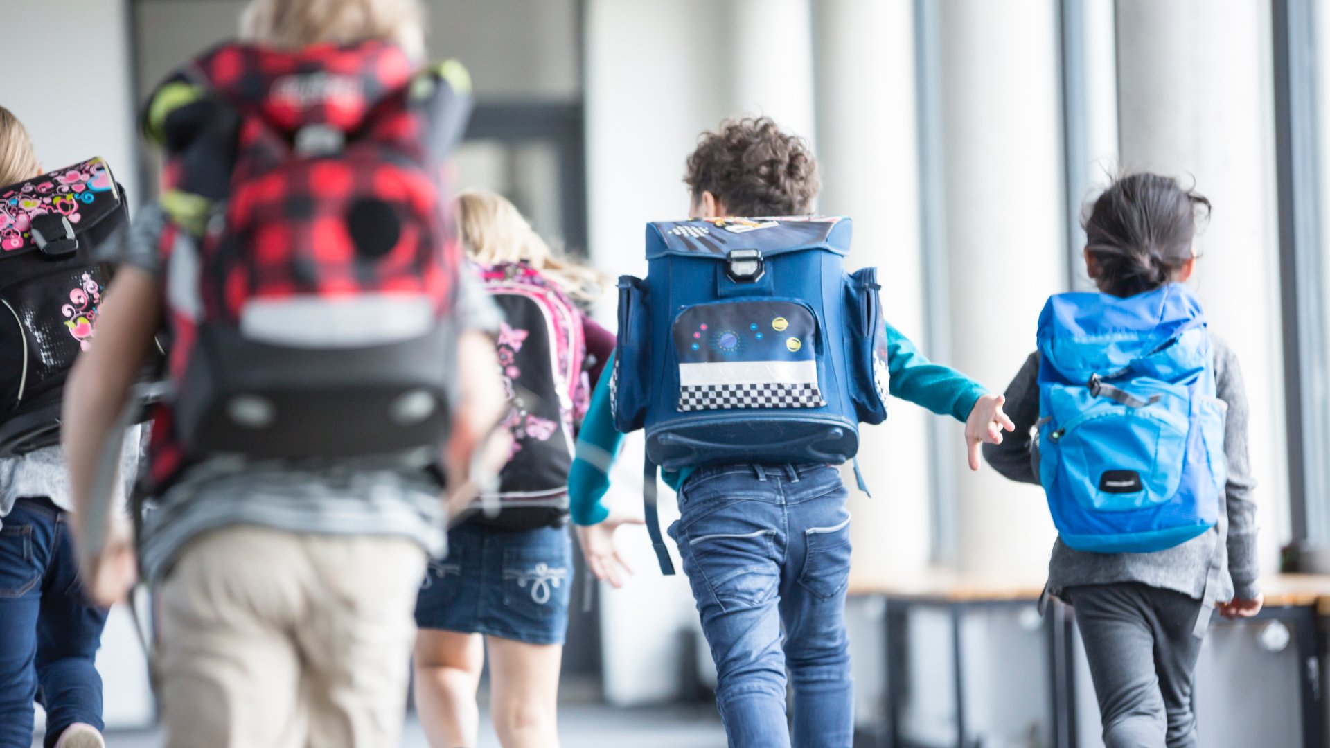 Gyerekek iskolatáskával a hátukon az iskola folyosóján