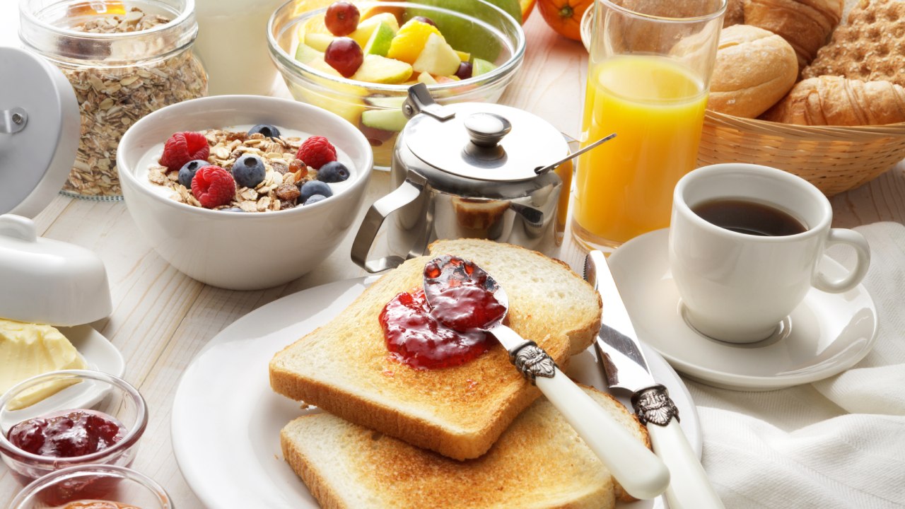 Ízletes reggeli: lekváros pirítós, kávé, joghurt, gyümölcsök.