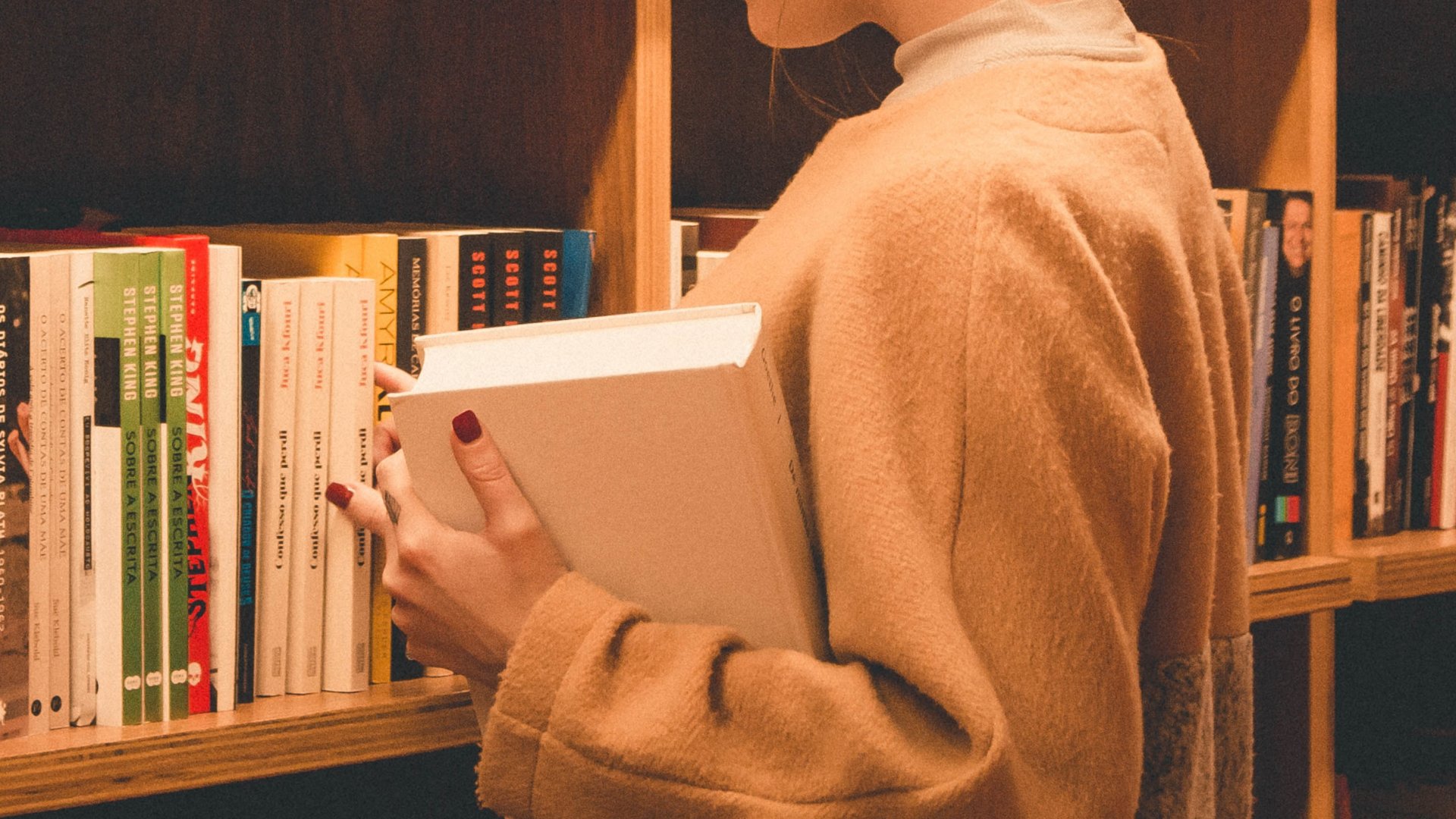 Könyvtári könyvek között válogat egy nő
