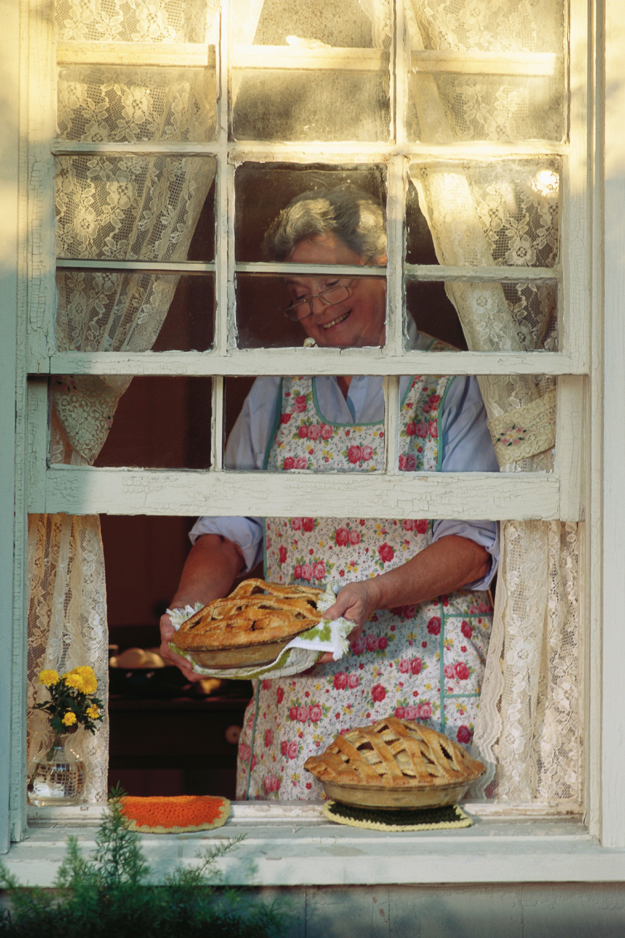 Illusztráció nagymamáról, aki almássütit helyez az ablakba.