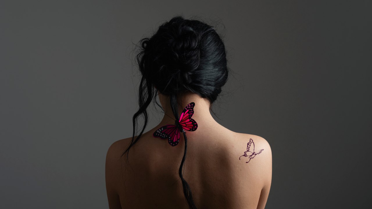 Háttal álló nő vállán pillangós tetoválás.