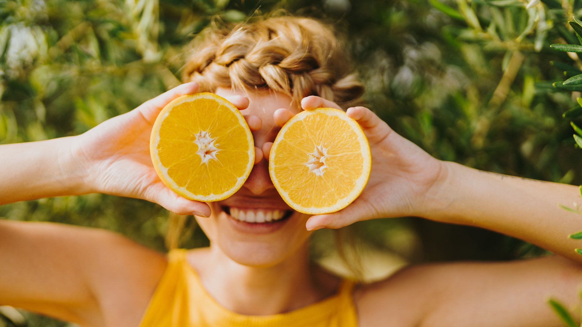 Egy fiatal nő félbevágott narancsokat tart a szeme előtt