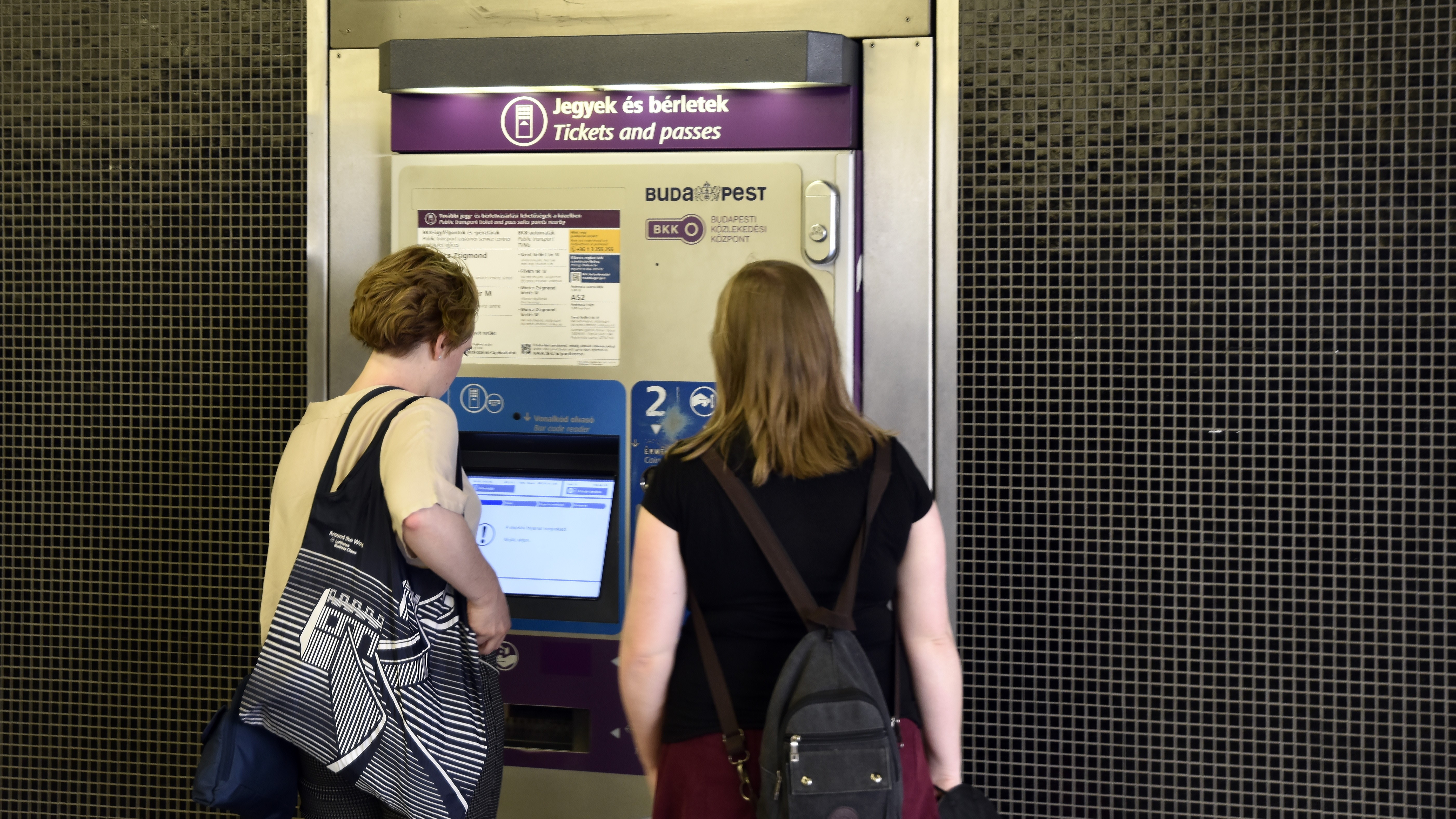 A BKK menetjegykiadó automatájából vásárolnak utasok jegyet a Szent Gellért tér-Műegyetem metróállomásnál