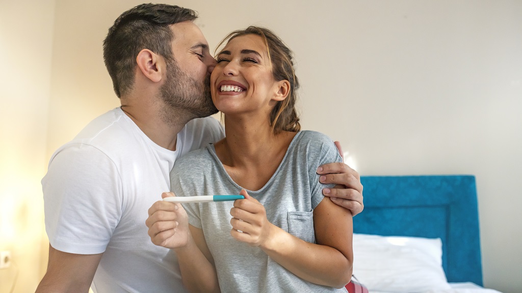 Boldog pár örül a pozitív terhességi tesztnek