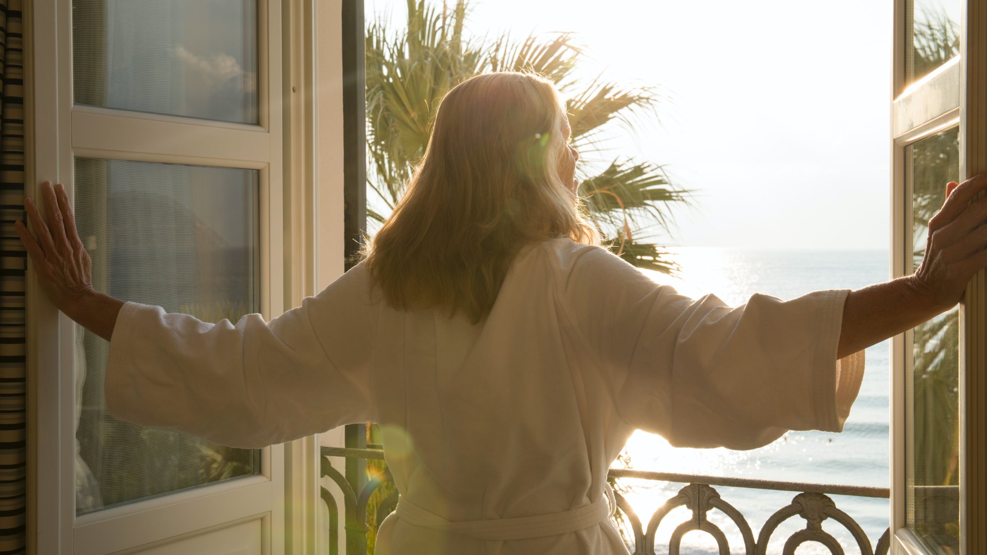 Egy nő kinyitja a tengerpartra néző ablakot