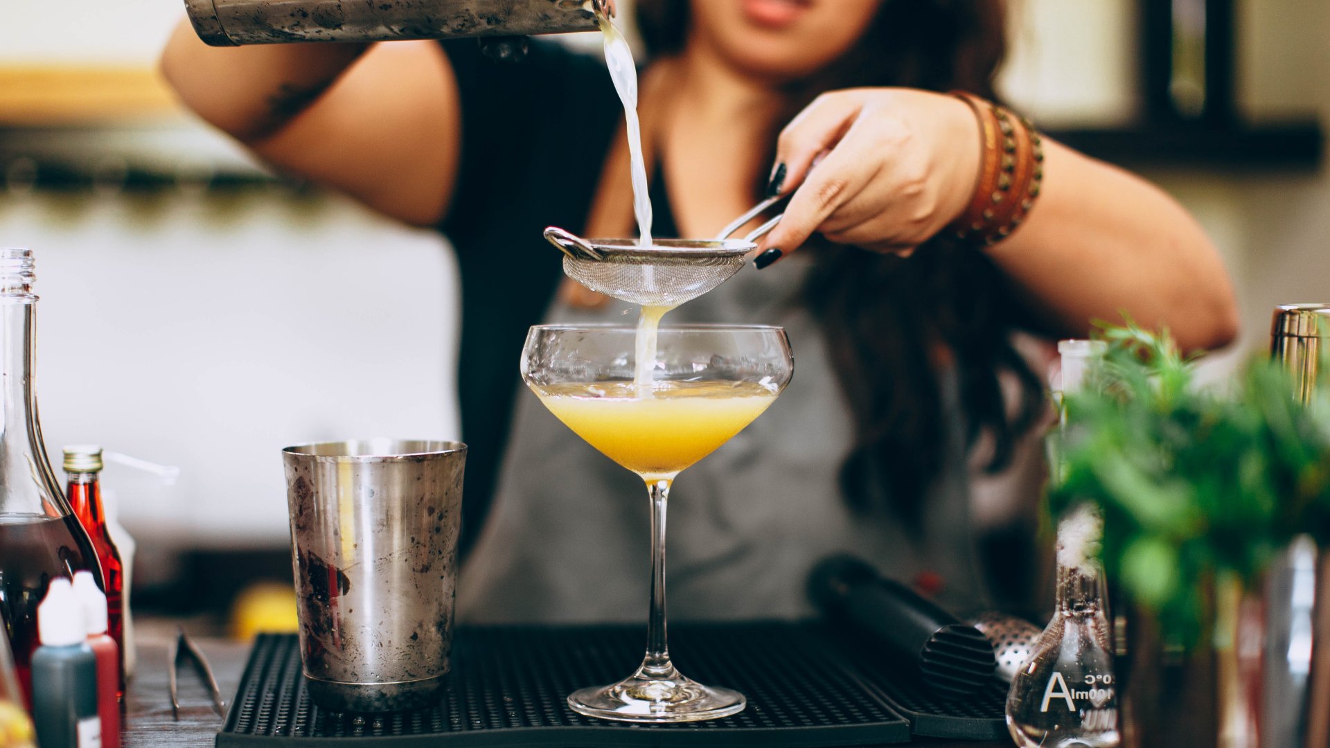 Egy női bartender koktélt készít a pult mögött