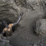 Egy fiatal kongói férfi ereszkedik le egy gödörbe