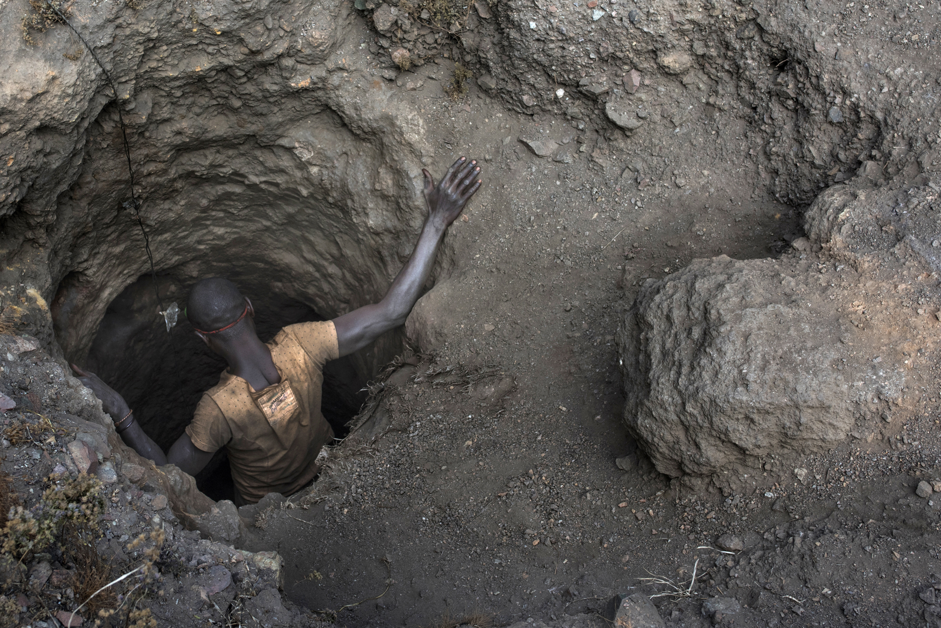 Egy fiatal kongói férfi ereszkedik le egy gödörbe