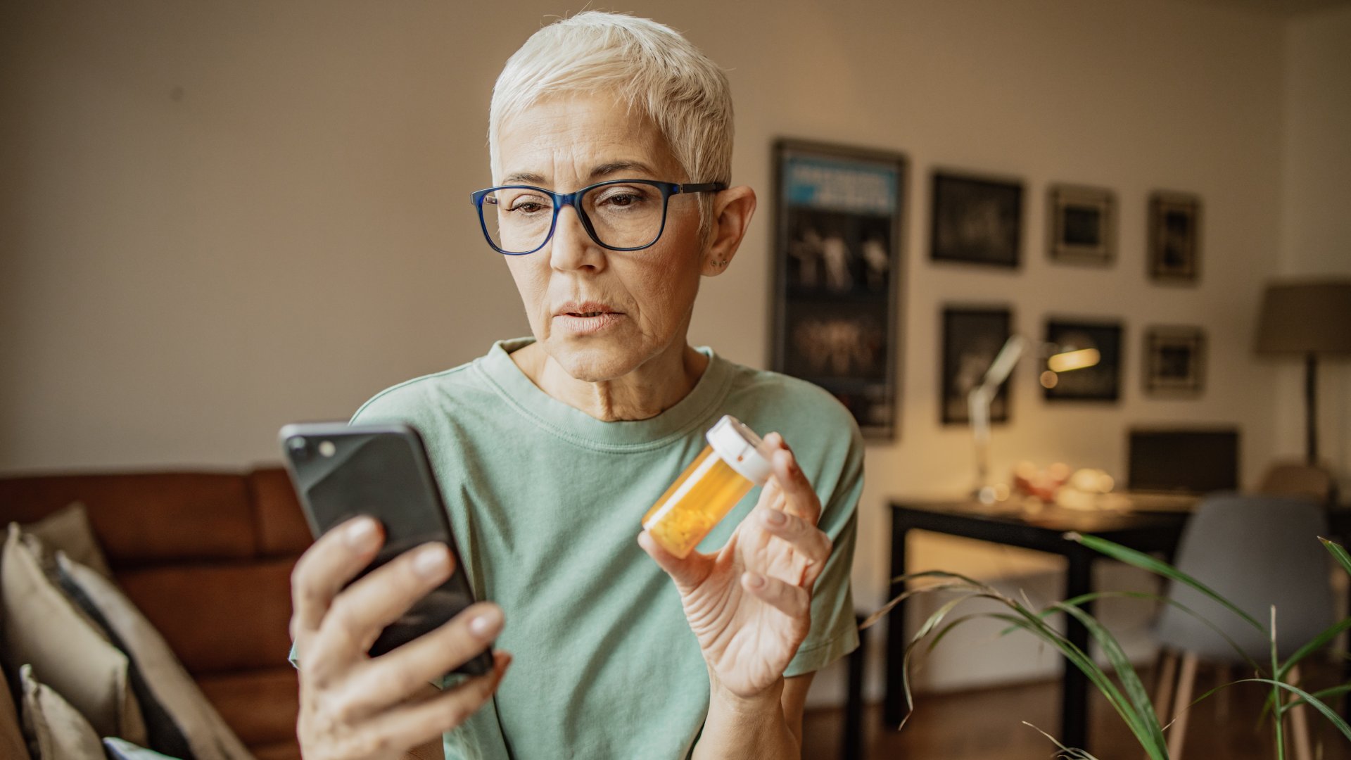 Idősebb nő információt keres a telefonján a kezében tartott gyógyszerről