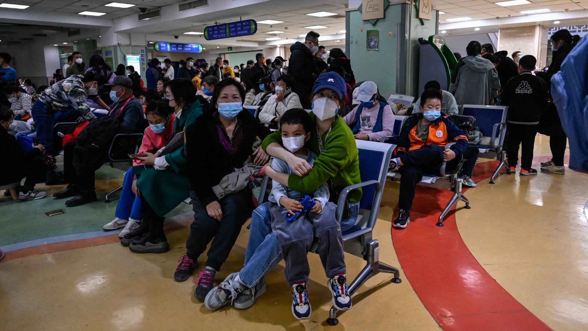 Gyermekek és szüleik várakoznak egy pekingi gyermekkórház járóbeteg-ellátó területén 2023. november 23-án