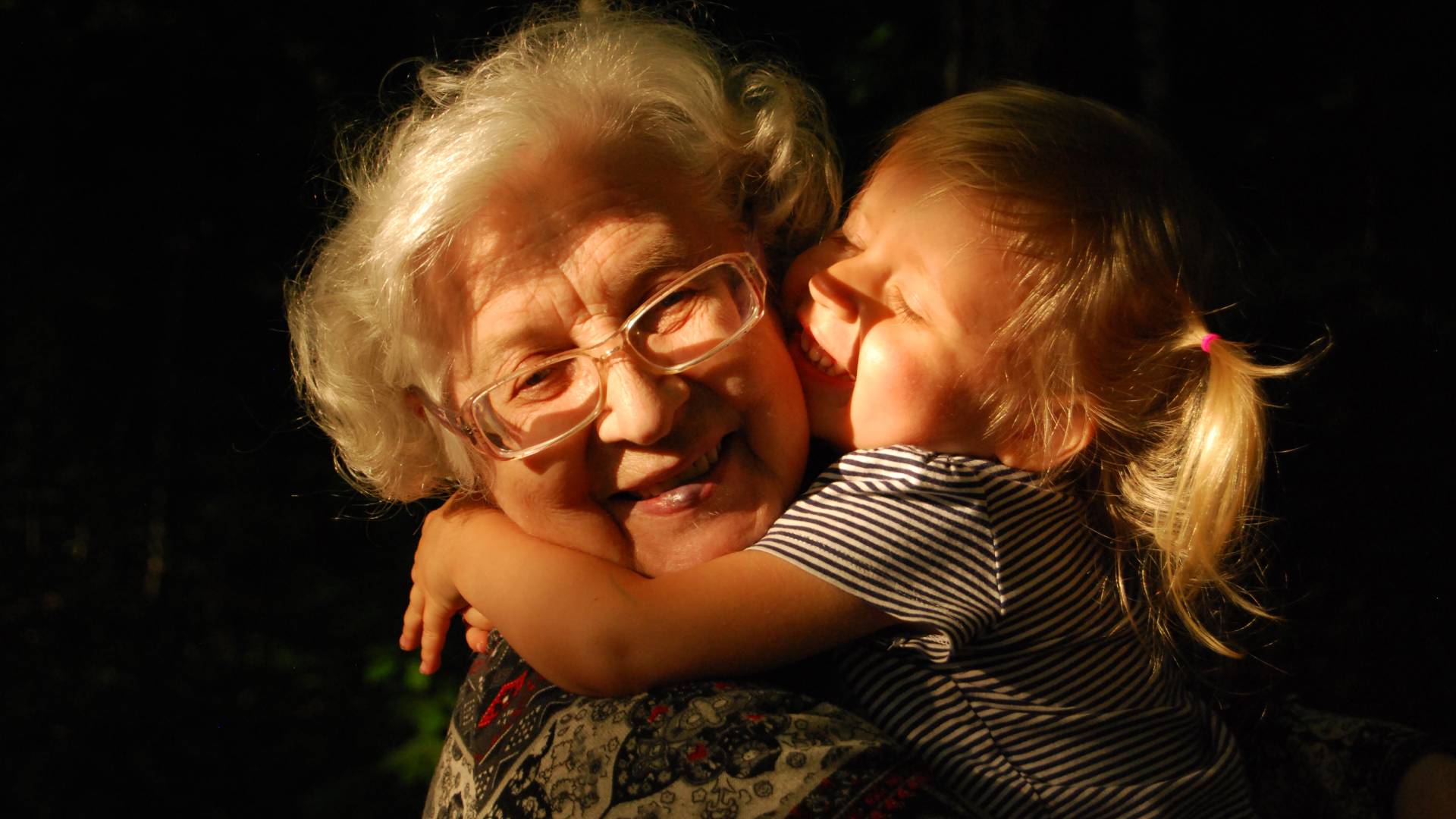 Idős nő ölel fiatal kislányt.