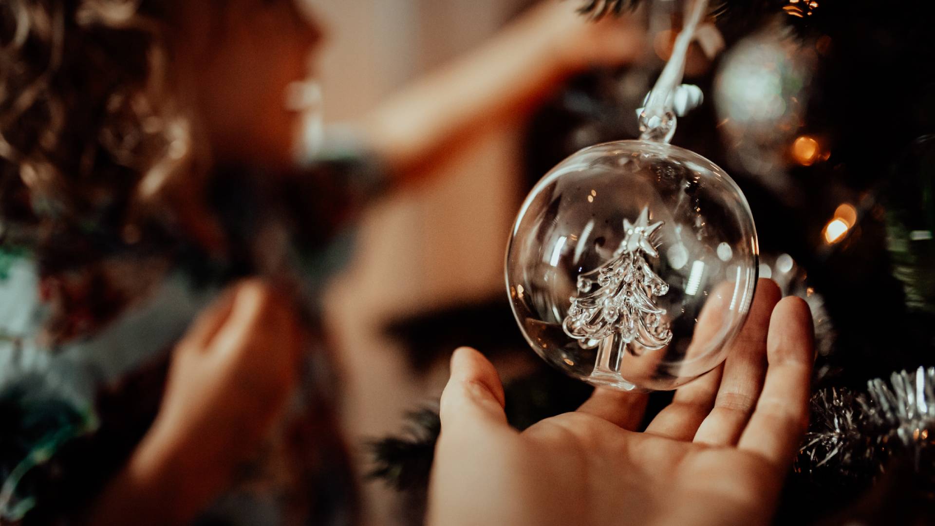 Karácsonyi üveggömböt tartó kéz.
