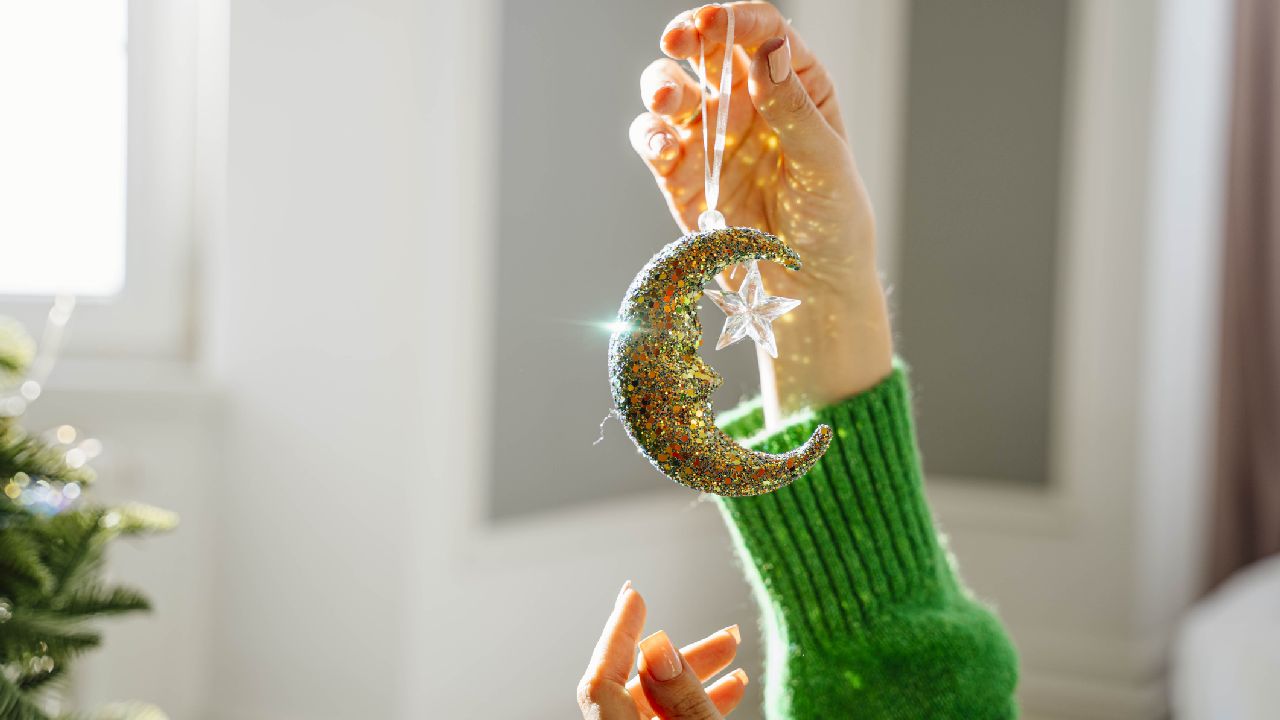 Hold alakú karácsonyfadíszt tart egy női kéz