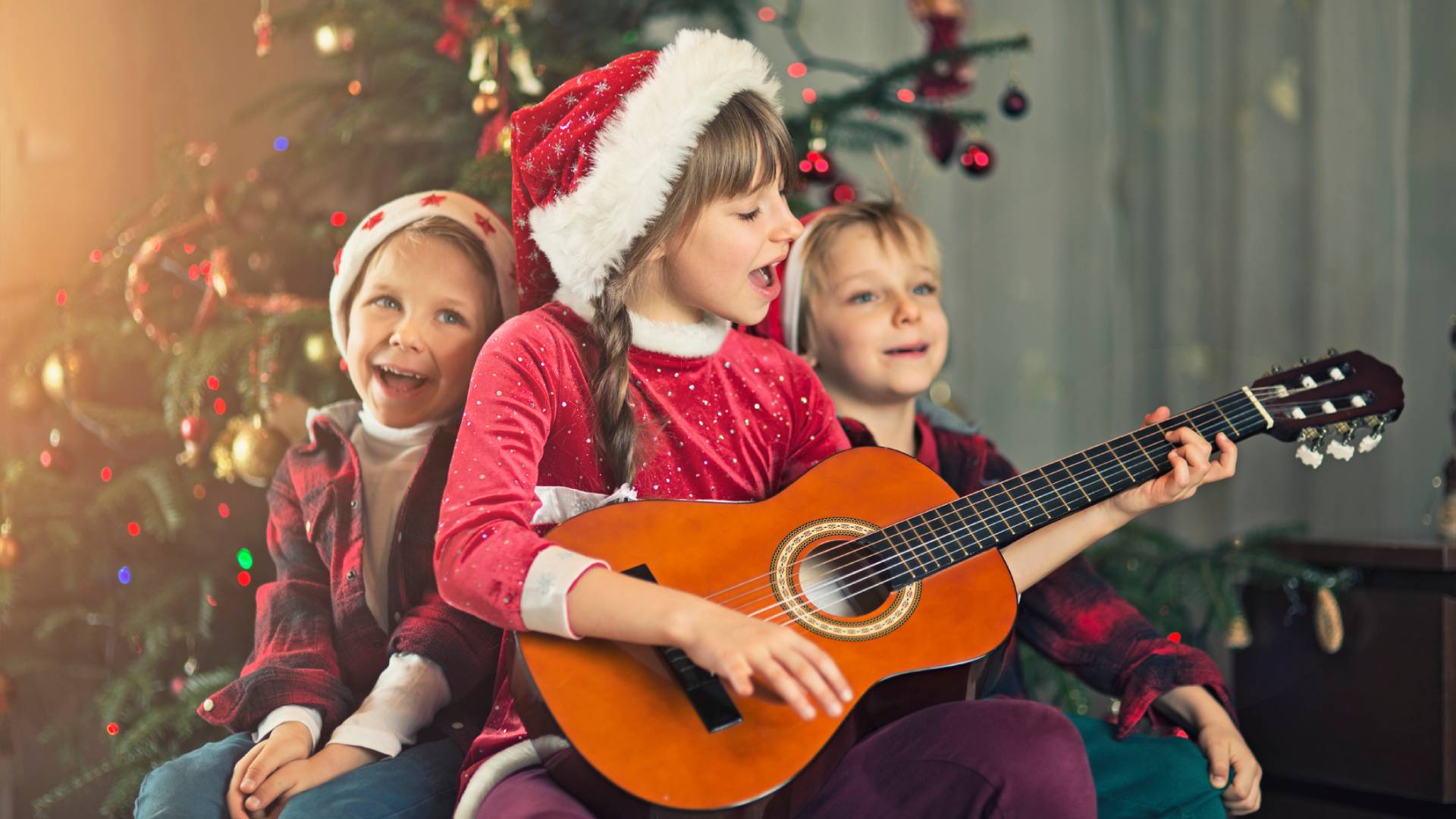 Éneklő gyerekek a karácsonyfa előtt.