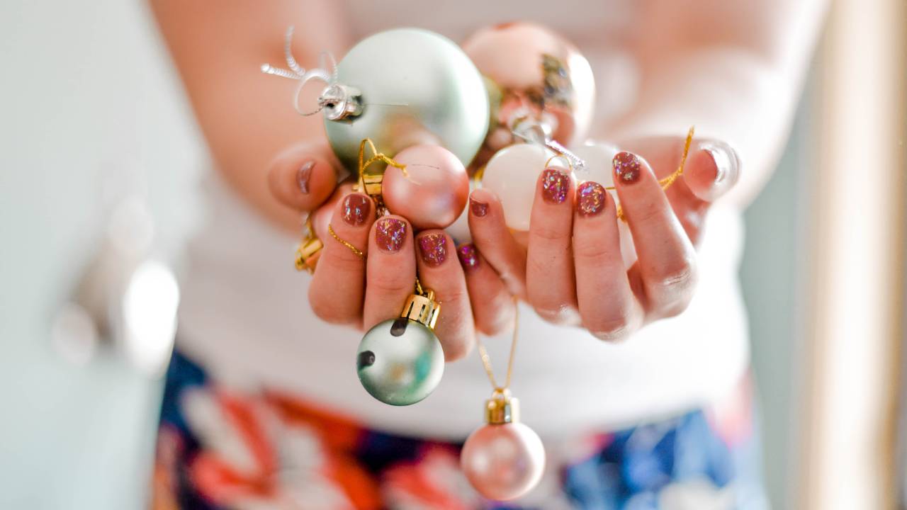 Karácsonyi gömböket tartó kéz.