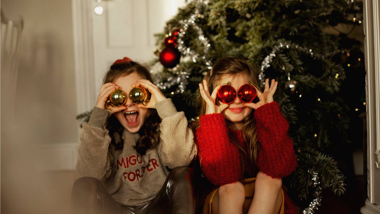 Kislányok karácsonyi gömböket tartanak a szemeik elé.
