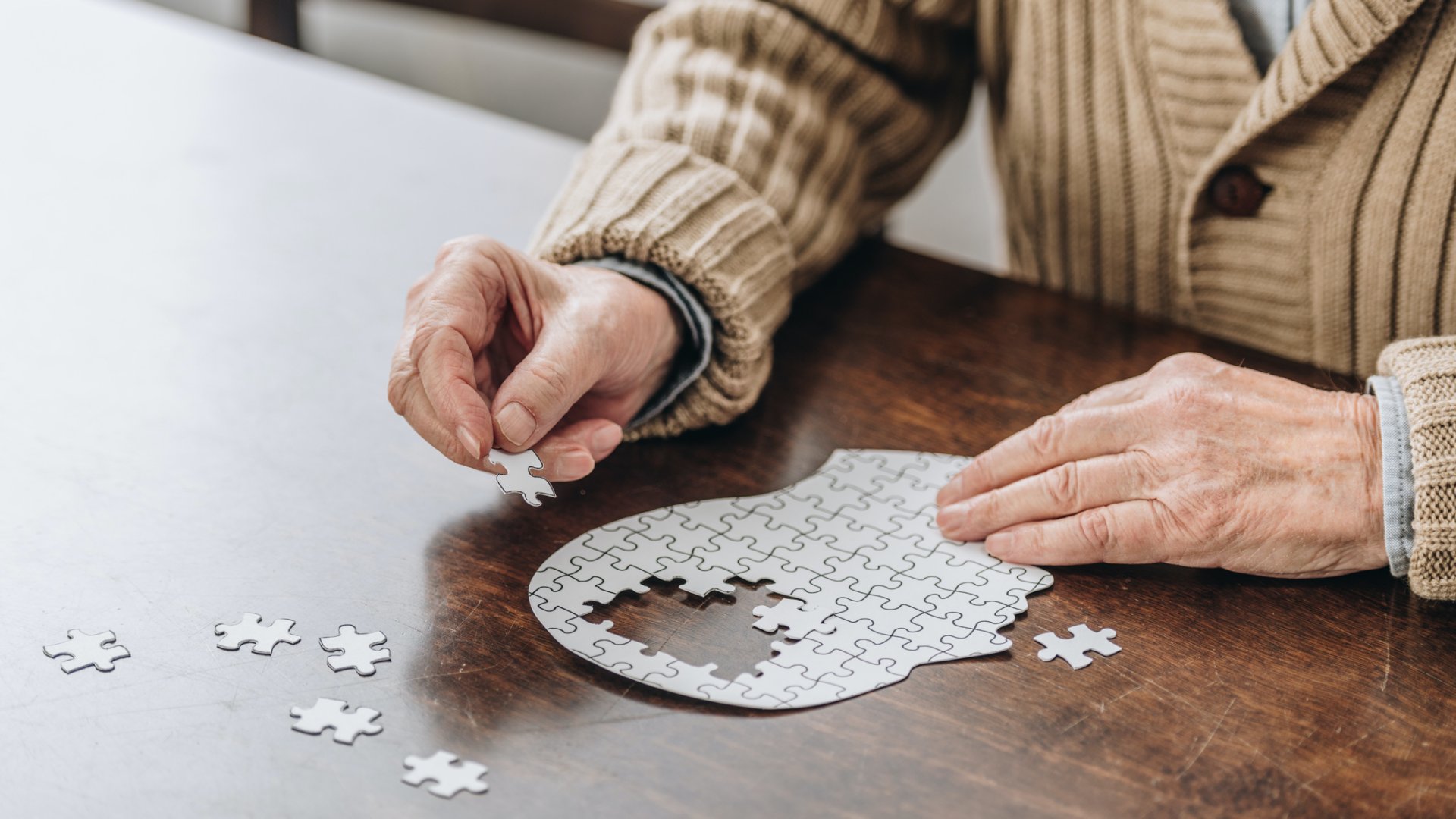 Egy idős férfi egy fej formájú puzzle-t rak ki