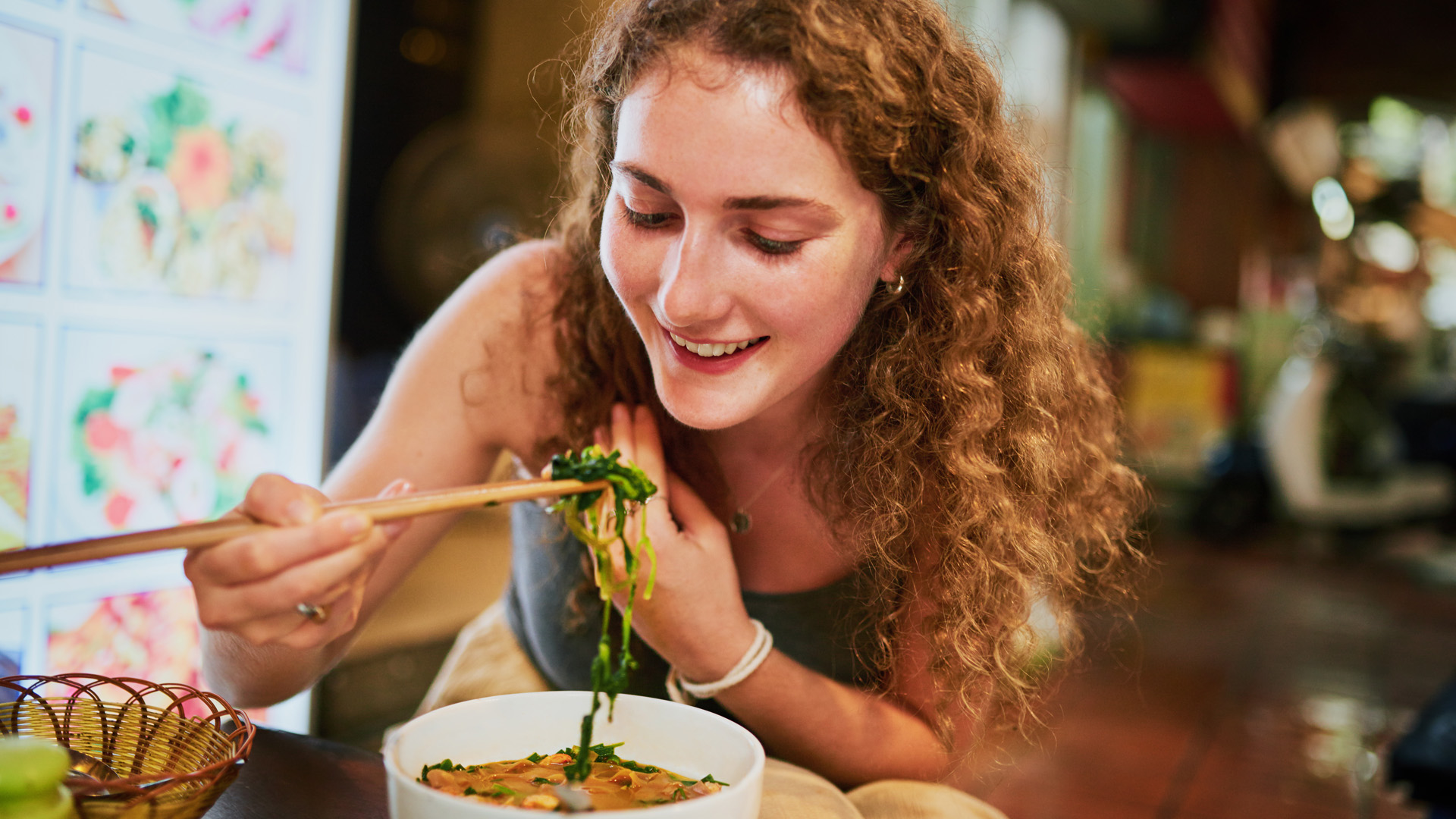 Evőpálcikával eszik egy nő egy étteremben