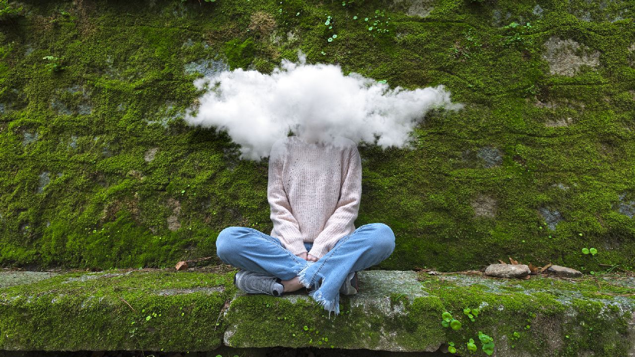 Lány ül a kövön, feje felhőben