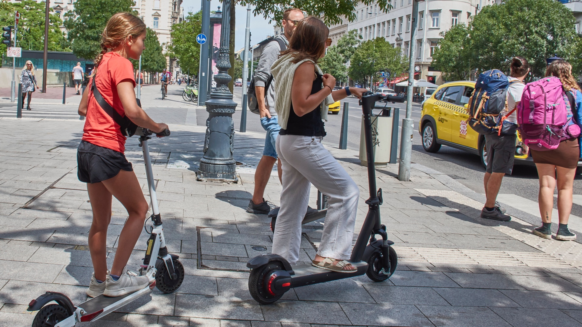 Elektromos rolleresek és gyalogosok várnak a szabad jelzésre Budapest belvárosában, a Bajcsy-Zsilinszky úton egy gyalogátkelõhelynél