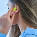Egy nő füldugót tesz a fülébe