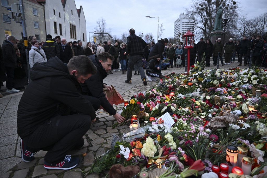 Az emberek gyertyákat gyújtanak és virágokat hagynak a Szent Johannis templom előtt, szemben a karácsonyi vásárral, ahol az autóval elkövetett merénylet történt, Magdeburgban, Németországban, 2024. december 21-én.